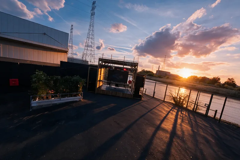 The open-air yard at Eutopia Warehouse at sunset, the outdoor stage by the river